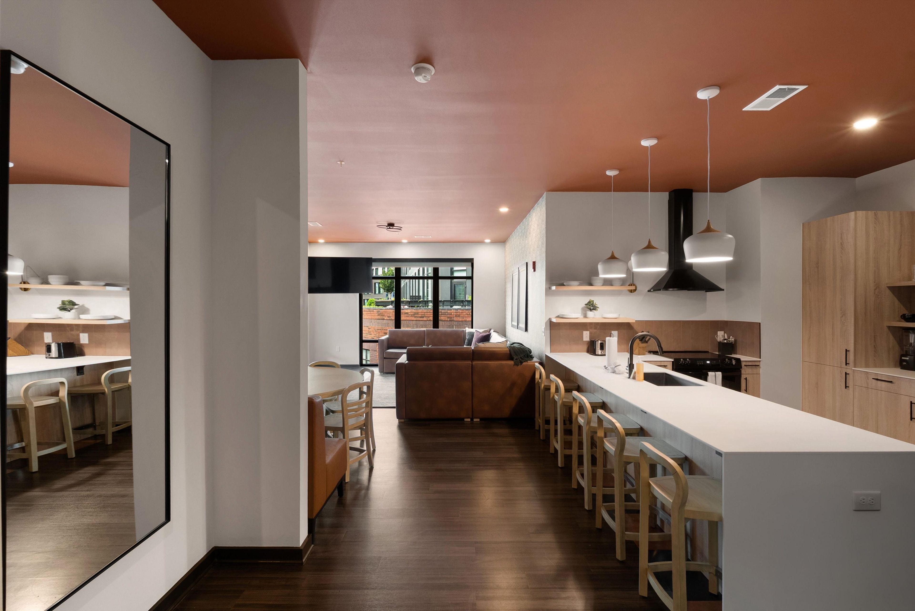 Una cocina moderna con una isla central, taburetes de bar y una zona de comedor con sofá.