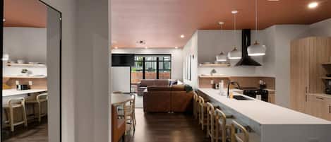 Una cocina moderna con una isla central, taburetes de bar y una zona de comedor con sofá.