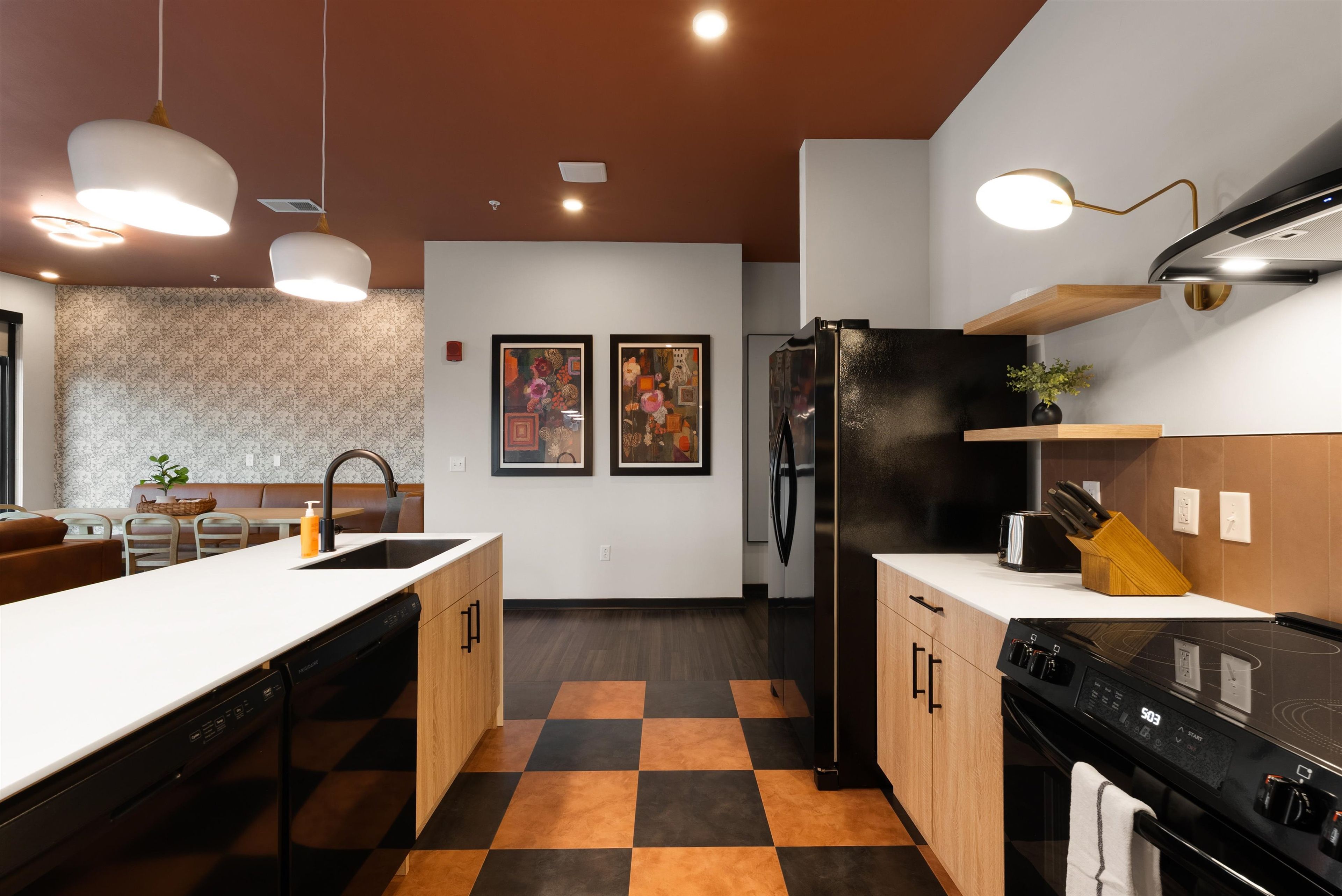 Una cocina moderna con piso a cuadros, un refrigerador negro y un lavavajillas.