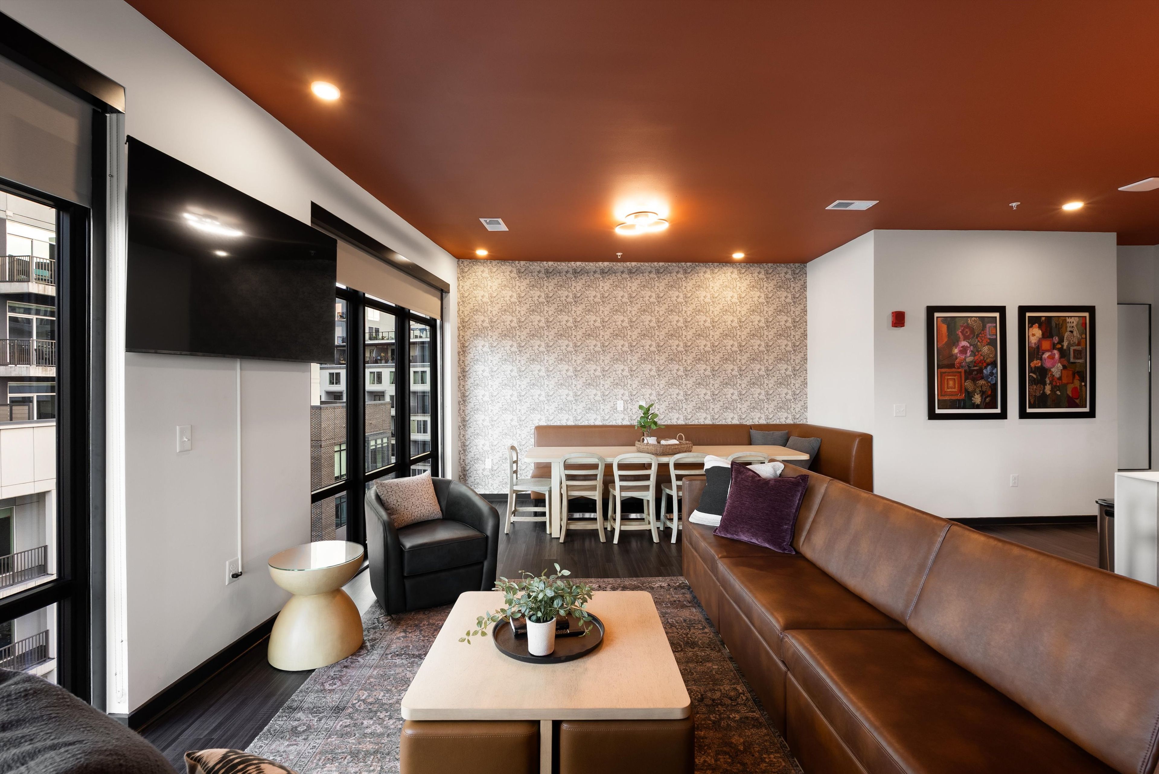 A modern living room with a sofa, coffee table, and a dining area with chairs and a table.