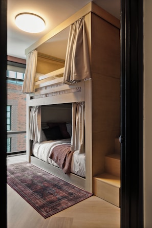 A bunk bed with curtains, a patterned rug, and a view of a brick building. - Superior Suite - Unit 401 (Nashville)