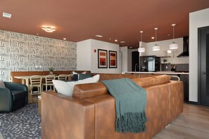 A modern living room with a brown leather sofa, a dining area with a table and chairs, and a kitchen with stainless steel appliances. - Superior Suite - Unit 401 (Nashville)