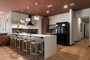 A modern kitchen with a central island, bar stools, a black refrigerator, and pendant lighting. - Superior Suite - Unit 401 (Nashville)