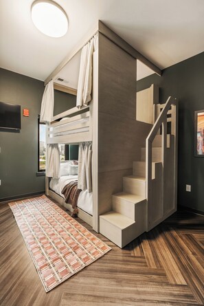 A compact room with a bunk bed, a staircase, and a large window. - Superior Suite - Unit 402 ADA-accessible (Nashville)