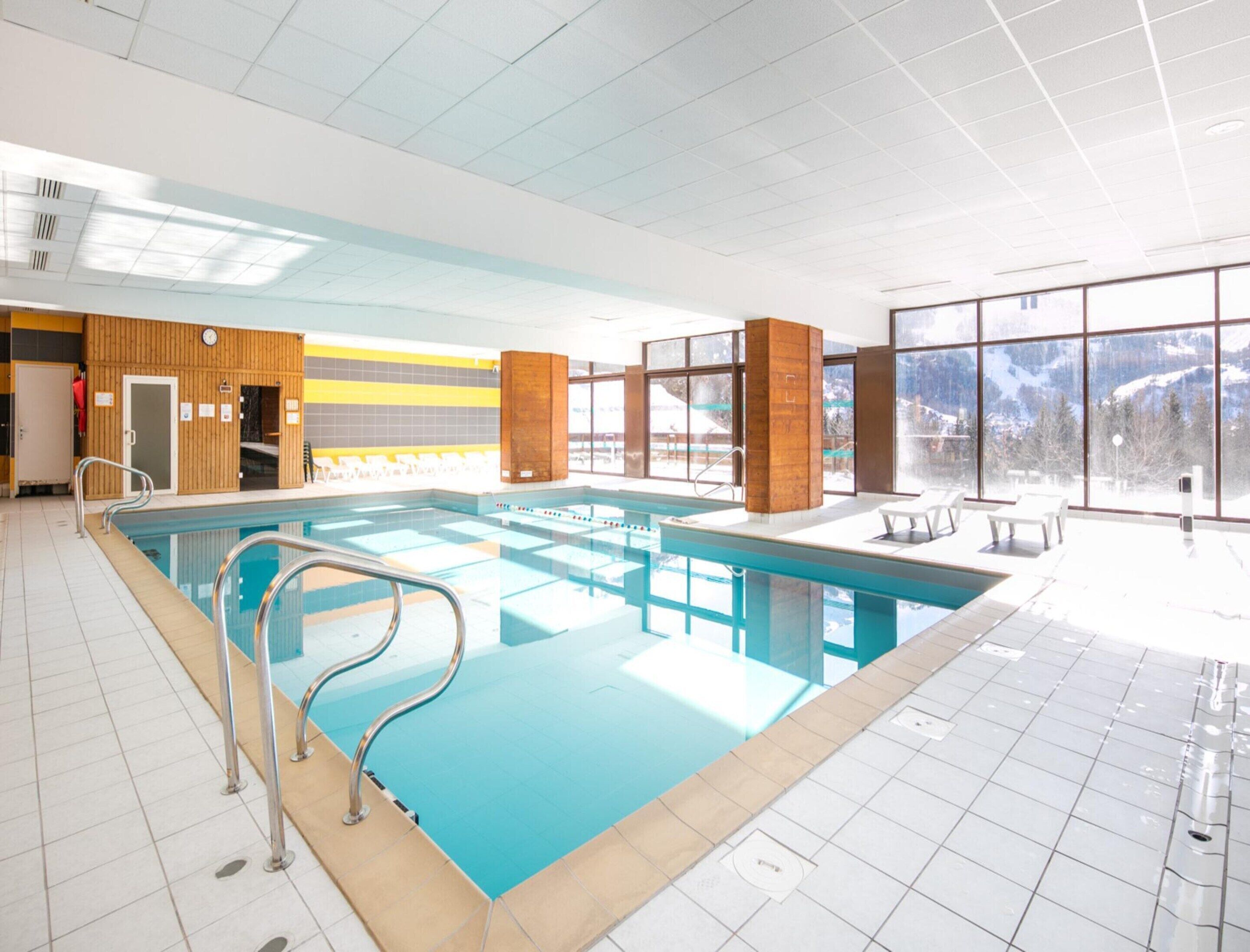 An indoor swimming pool with clear views of mountains through large windows.