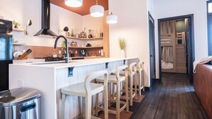 A modern kitchen with a central island, bar stools, a built-in stove, and pendant lighting.