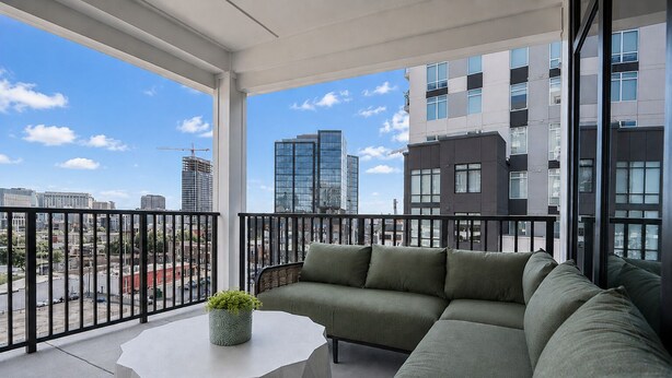 A balcony with a sofa, a round table, and a potted plant.