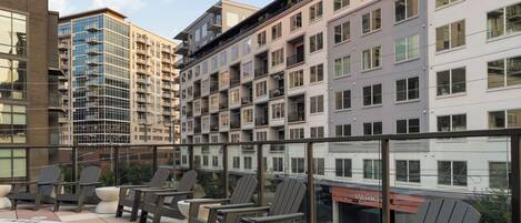 A rooftop pool area with lounge chairs and a view of surrounding buildings.