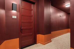 Un pasillo con una puerta roja, un cartel con un número y una cámara de seguridad.