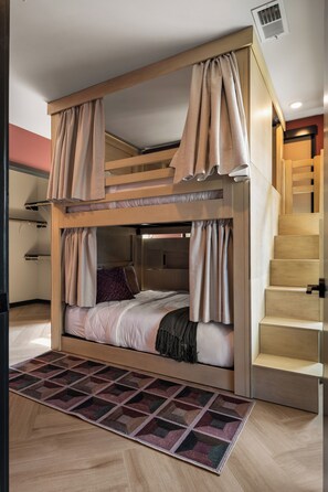 Una cama tipo litera con cortinas, una alfombra estampada y una escalera.