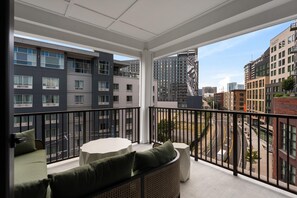 Een balkon met uitzicht op omliggende gebouwen, een tafel en zitplaatsen.