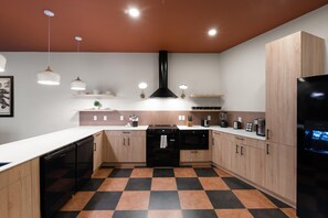 A modern kitchen with a checkered floor, wooden cabinets, and stainless steel appliances. - Superior Suite - Unit 702 (Nashville)