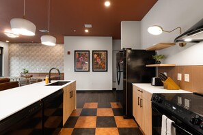 A modern kitchen with a checkered floor, a black refrigerator, and a dishwasher. - Superior Suite - Unit 706 (Nashville)