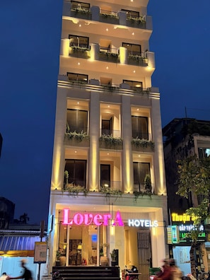 A multi-story hotel with balconies, a neon sign, and a storefront.
