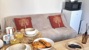 Un salon confortable avec un canapé, une table basse et une table à manger dressée pour le petit-déjeuner.
