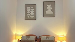 Une chambre d’hôtel avec un lit, deux lampes fixées au mur et deux œuvres d’art encadrées.