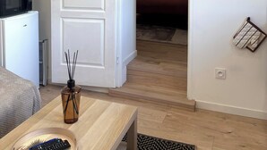 Une pièce avec une porte blanche, une horloge au mur, un four à micro-ondes et une petite table sur laquelle se trouve une télécommande.