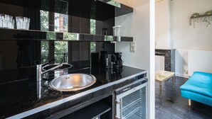 A modern kitchen with a black countertop, stainless steel sink, and a built-in dishwasher. - 1-bedroom Apartment in National Residence (Antwerp)