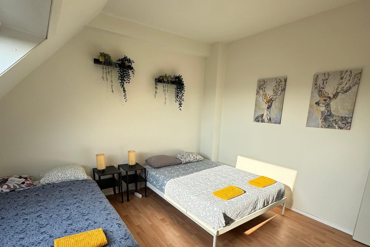 Un dormitorio con dos camas, ventilador de techo y plantas en la pared.