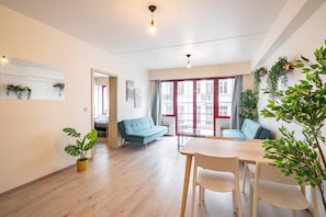 A modern living room with a sofa, a dining table, and potted plants.