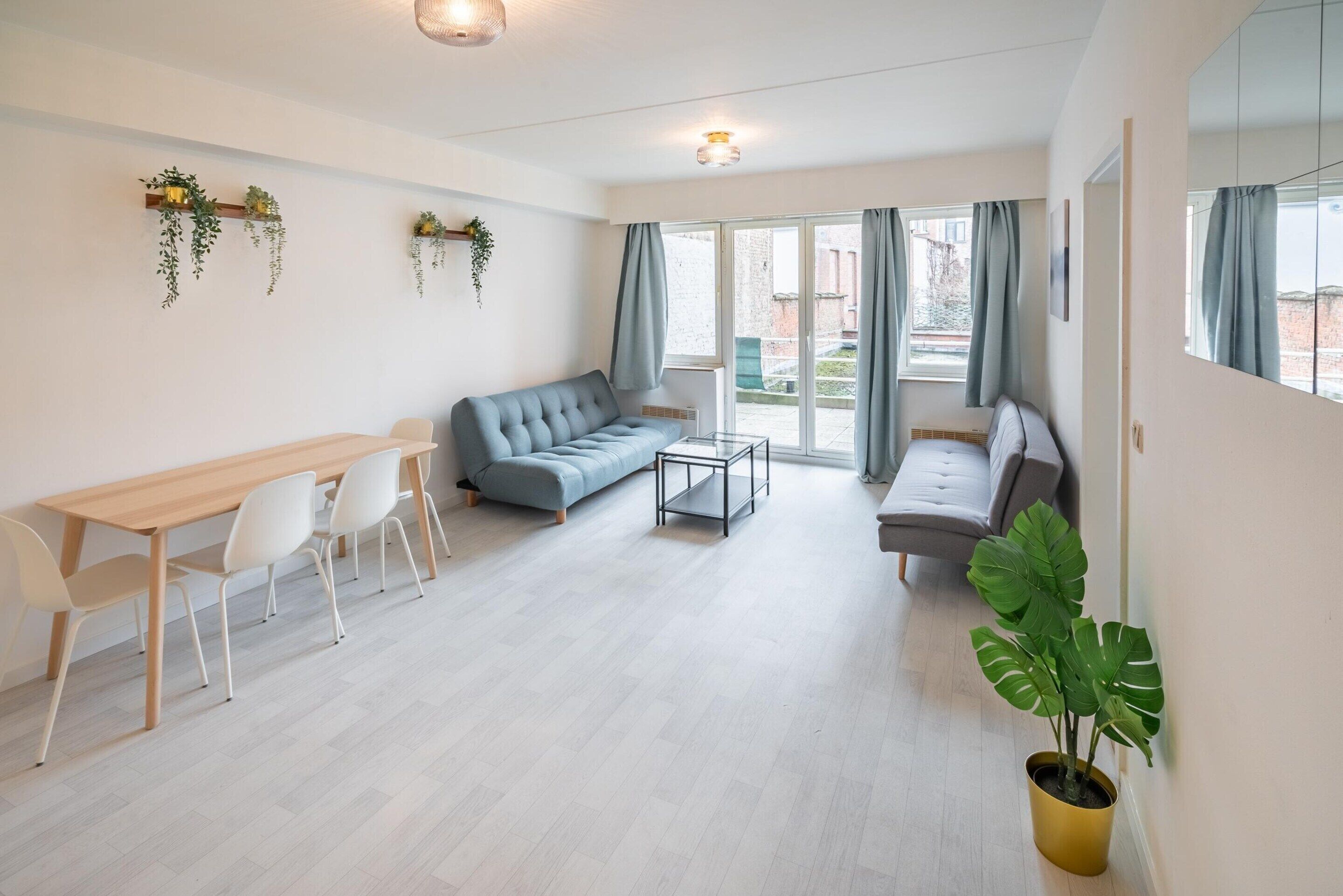 Una sala moderna con un sofá, una mesa de comedor con sillas, una mesa de centro y una planta en maceta.