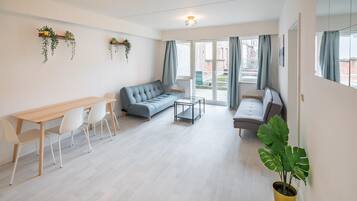 Una sala moderna con un sofá, una mesa de comedor con sillas, una mesa de centro y una planta en maceta.