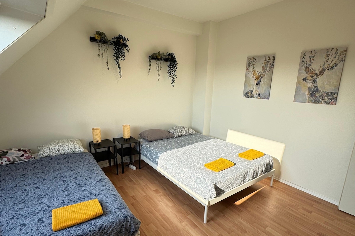 A bedroom with two beds, a ceiling fan, and wall-mounted plants.