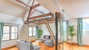 A loft-style room with a wooden ceiling, a sofa, a coffee table, and a ladder. - Temple Triplex Spacious Apartment (Antwerp)