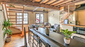 A modern kitchen with wooden beams, a dining area with a long table, and a staircase leading to an upper floor. - Temple Triplex Spacious Apartment (Antwerp)