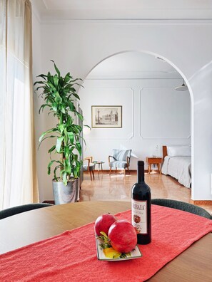 A room with a dining table, a potted plant, a framed picture, a bed, and a chair. - Bright 1-Bedroom Apartment with Iconic Basilica Balcony (Roma)