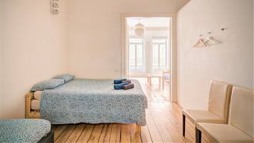 A bedroom with a bed, a bench, a hanging light fixture, and a door leading to a balcony.