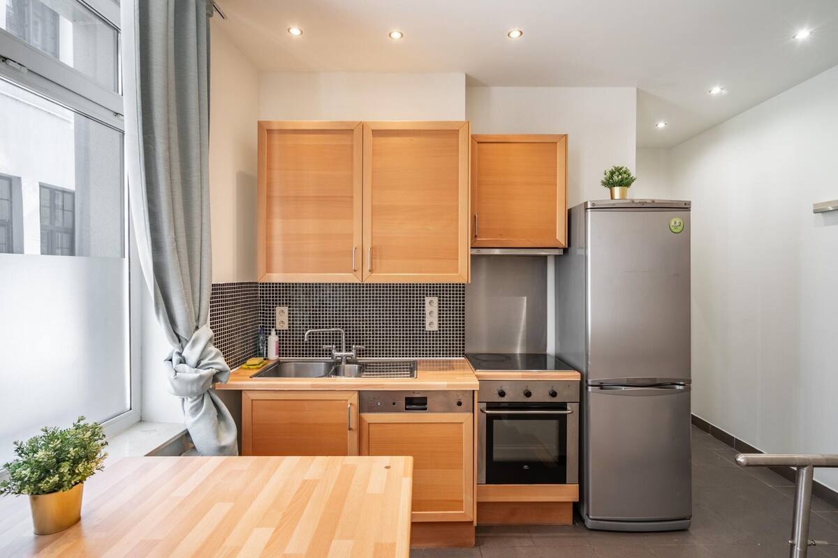 A modern kitchen with wooden cabinets, a stainless steel refrigerator, and a built-in oven.
