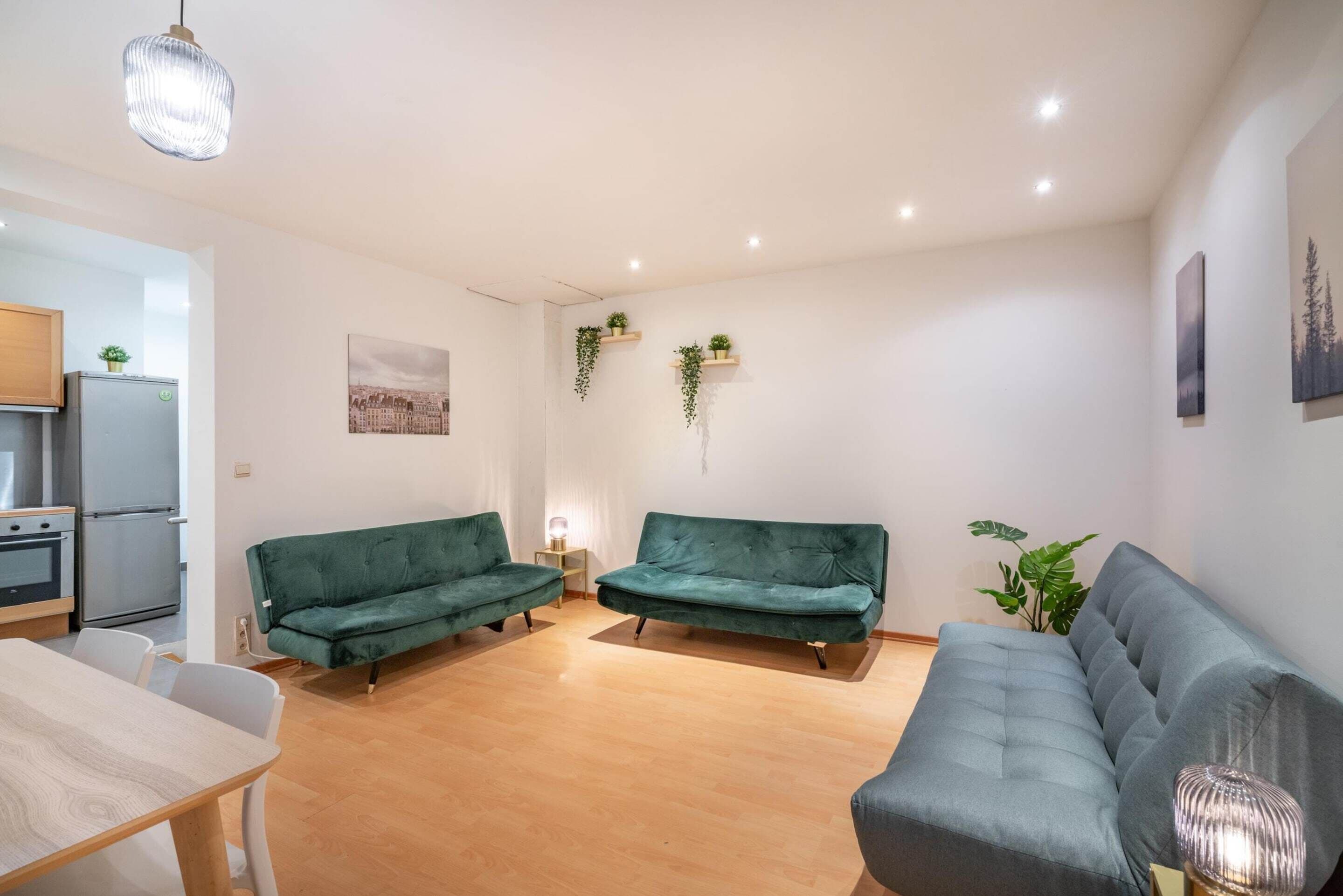 A modern living room with a sofa, a dining table, and a kitchen area.