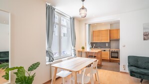 Um apartamento moderno com área de refeições, cozinha e sofá verde.