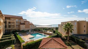 A hotel with a swimming pool, a covered patio, and a view of the beach.