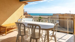 A balcony with a table and chairs, overlooking a beach and the sea. - Large Seaview Stay for 8 in Valras Plage (Valras-Plage)