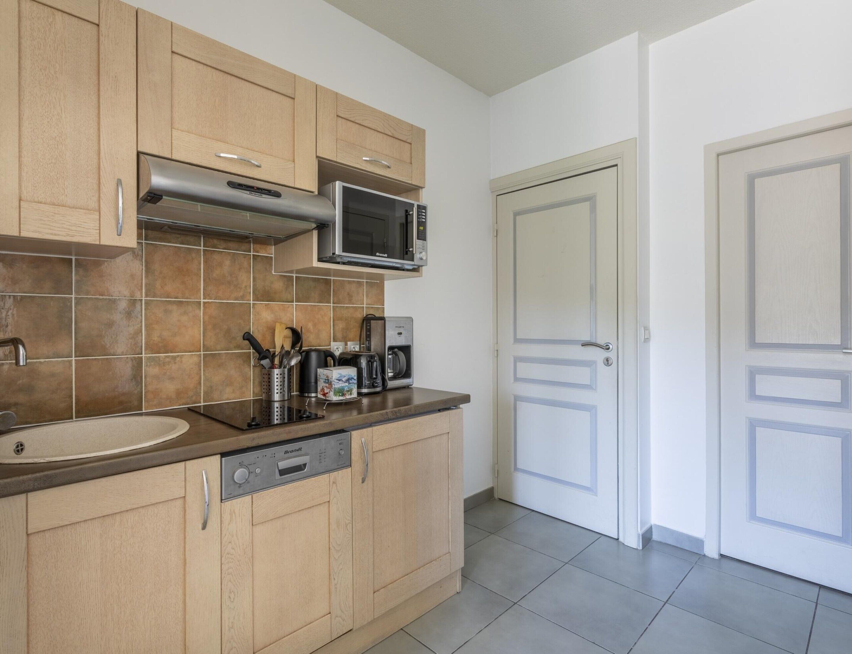 A kitchen with wooden cabinets, a stainless steel microwave, a coffee maker, and a dishwasher.