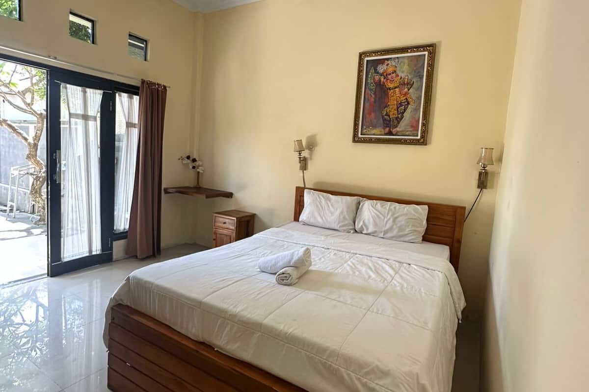 Un dormitorio con una cama, un cuadro, una mesita de noche y una puerta que da a un balcón.
