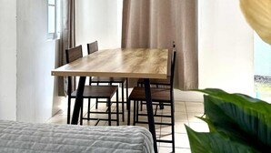 A modern dining area with a wooden table and chairs, a window, and a curtain. - Delightful 3-bedroom bungalow with AC in charming Dauis (Dauis)