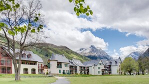 A traditional European-style hotel with multiple buildings, a central courtyard, and a mountain backdrop. - 4-guest Studio Near Thermal Baths (Loudenvielle)