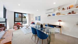 Ein modernes Wohnzimmer mit einem Glastisch, blauen Stühlen, einem Sofa und einem Couchtisch.