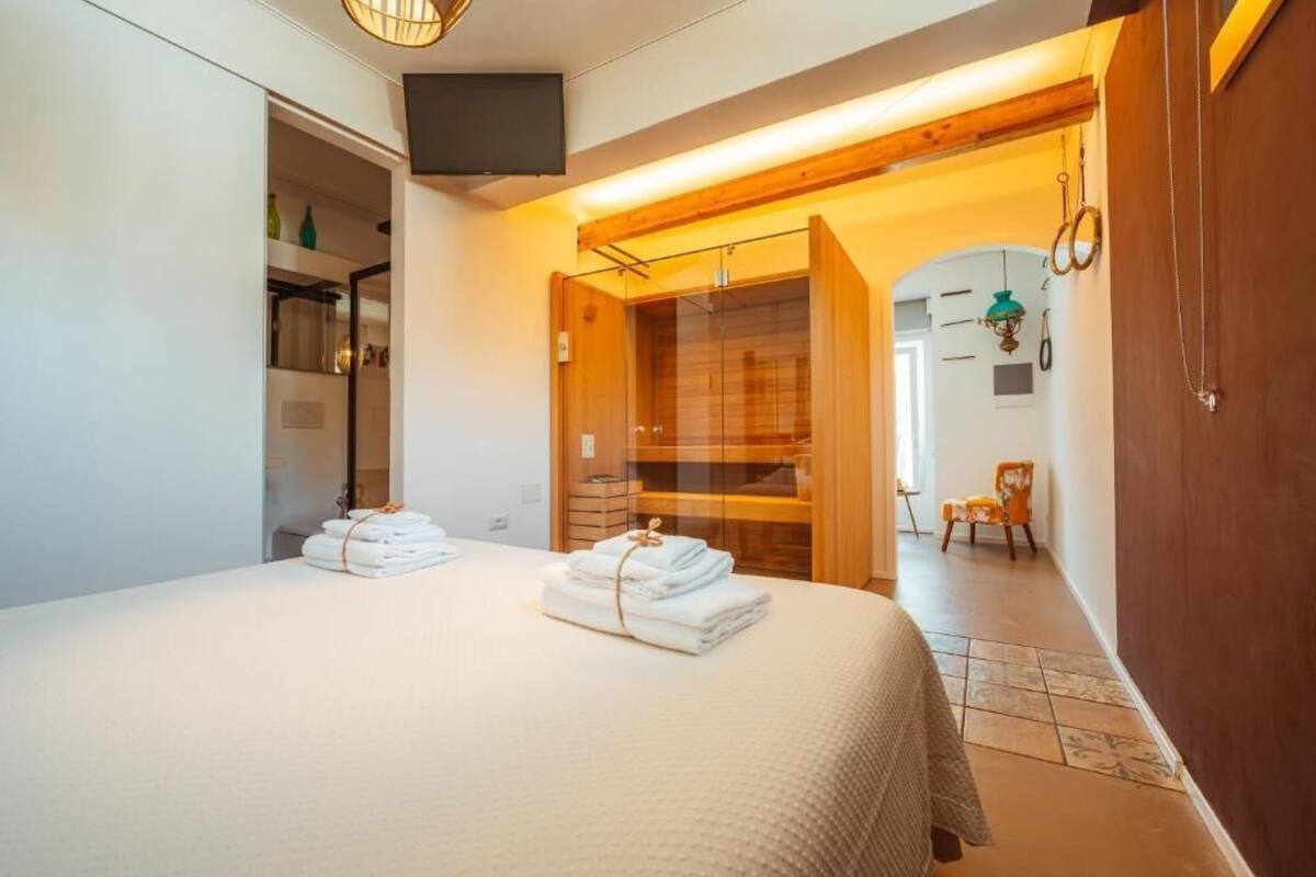 A hotel room with a large bed, a wooden wardrobe, a walk-in closet, and a TV mounted on the wall.