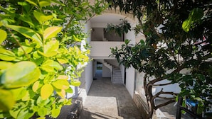 A stone pathway leading to a white building with a staircase and a small balcony. - Goldie Home by RentalsPro - Kallithea Halkidiki (Kallithea)