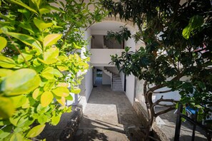 A stone pathway leading to a white building with a staircase and a small balcony. - Goldie Home by RentalsPro - Kallithea Halkidiki (Kallithea)