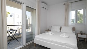 Ein Hotelzimmer mit Bett, Nachttisch, Fenster und einer Glastür, die zu einem Außenbereich führt.