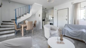 Ein modernes Interieur mit Treppe, Essbereich, Sofa und Küche.