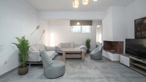 Ein modernes Wohnzimmer mit einer Couch, zwei Sitzsäcken, einem Couchtisch, einem Kamin und einem Fernseher.