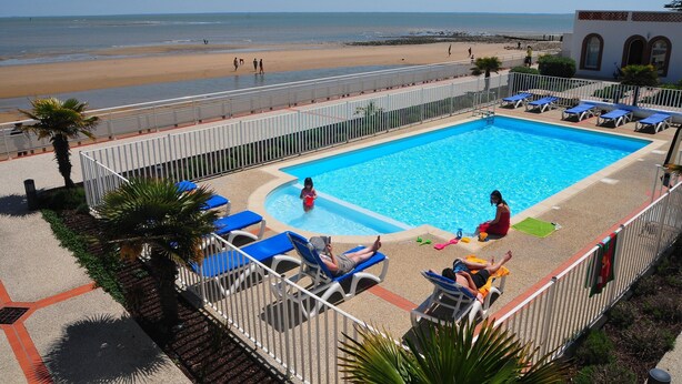 A swimming pool with a view of the beach, sun loungers, and a palm tree. - Coastal Apartment Near Beach for 4 (La Tranche-sur-Mer)