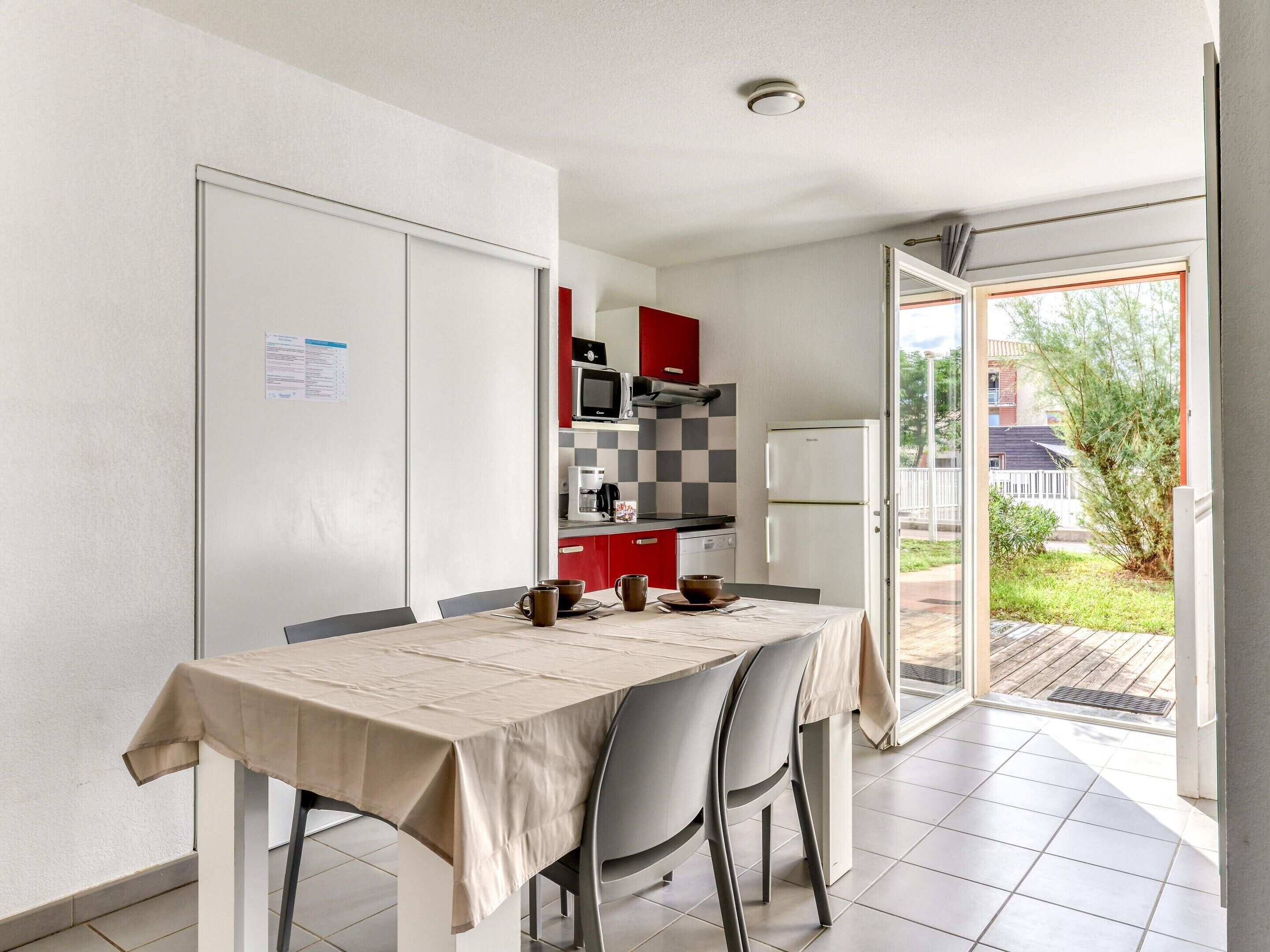 A modern kitchen with a dining area, a refrigerator, a microwave, and a coffee maker.