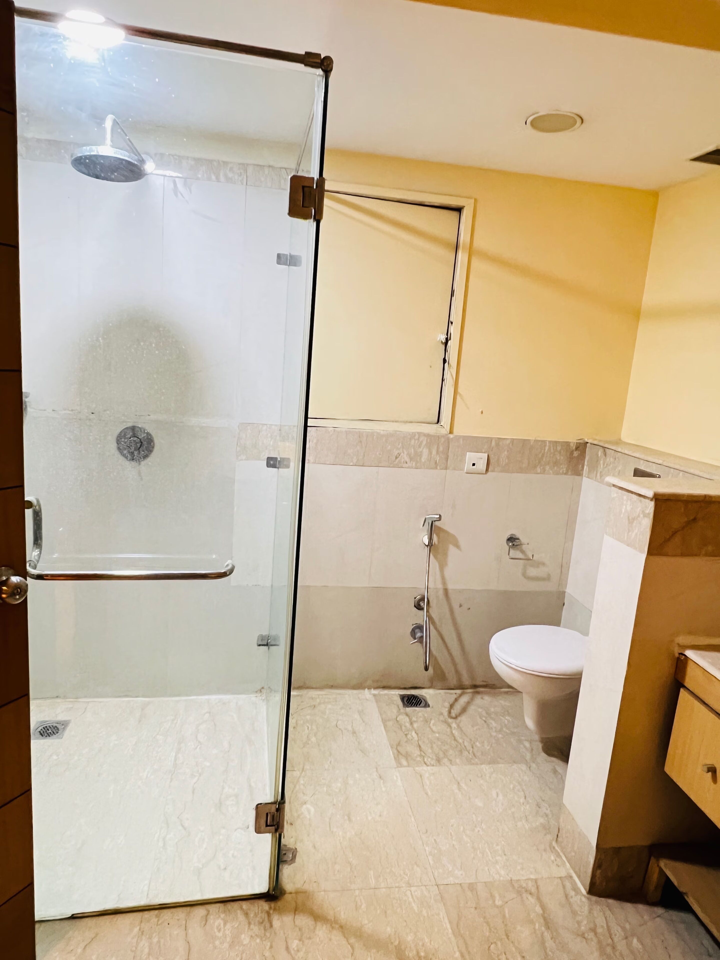 A bathroom with a glass shower enclosure, a toilet, and a sink.